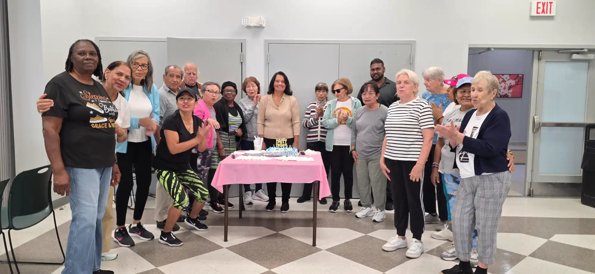 Large group gathered around a celebration table with cake