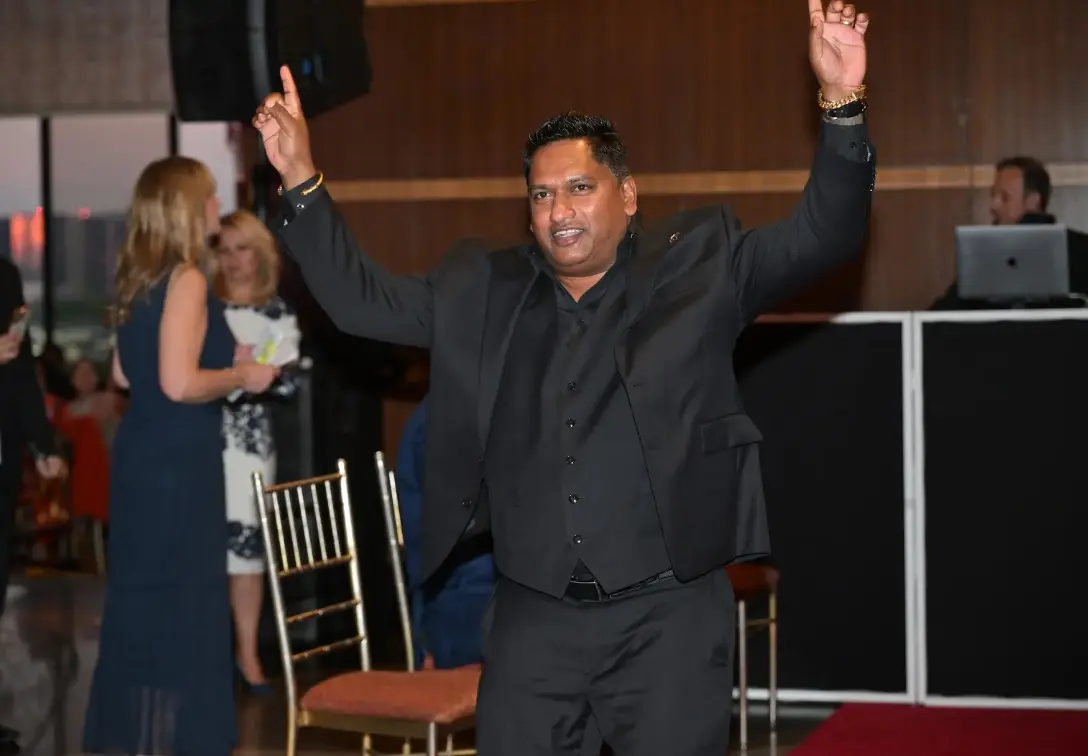 Navin Shivpal celebrating with arms raised at the awards evening reception